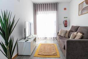 uma sala de estar com um sofá e uma televisão em O Cardanho dos Galfarritos - A Casa dos Miúdos em Aveiro