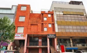 un edificio rosso con un cartello davanti di Om Sai Nath Hotel & Restaurant By WB Inn ad Agra