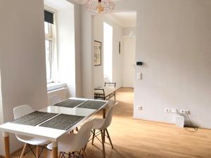 uma sala de jantar branca com uma mesa e cadeiras brancas em Classic, Modern&Charming! 7min to Vienna’s center! em Viena