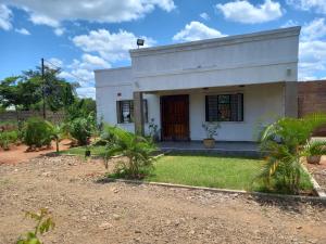 una casa blanca con un patio con palmeras en Kasuba Apartments en Livingstone