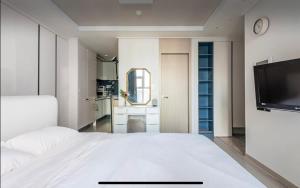 a bedroom with a white bed and a flat screen tv at Urban Exit Studio Gangnam in Seoul