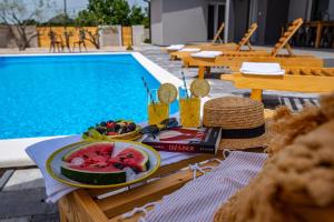 - une table avec une assiette de fruits à côté de la piscine dans l'établissement Villa Grigia, à Banjevci