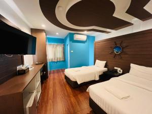 a hotel room with two beds and a flat screen tv at Bed By Cruise Hotel At Samakkhi-Tivanont in Nonthaburi