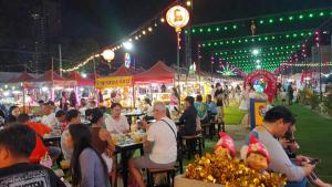 Un grupo de personas sentadas en mesas en un mercado por la noche. en 2 beds front beach, en Jomtien Beach 71 fotos más