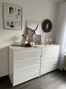 een witte dressoir in een witte kamer met een dressoir bij Quartier Lookvenne Wohnung 1 in Emden