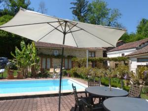 una mesa con sombrilla frente a una piscina en Le Moulin du Chemin, en Scillé