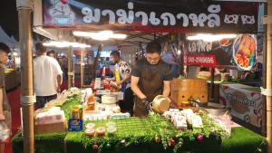 un hombre preparando comida en un puesto de comida en un mercado en 2 beds front beach, en Jomtien Beach