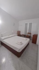 a large bed in a white room with chairs at Villas Estrellas 11 in Ciutadella