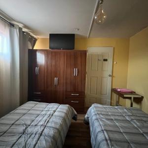 1 dormitorio con 1 cama y armario con TV en alojamiento diario con baño compartido, en Calama