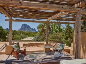 eine hölzerne Pergola mit 2 Stühlen und einem Tisch in der Unterkunft Kasbah 1 in Cala Vadella