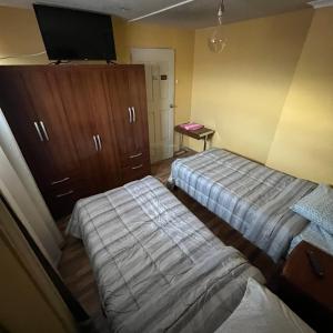 1 dormitorio con 2 camas y TV de pantalla plana en alojamiento diario con baño compartido, en Calama