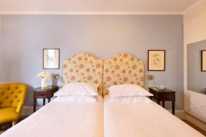 ミコノス・シティにあるクネニ アパートメンツのベッドルーム1室(ベッド2台、黄色い椅子付)