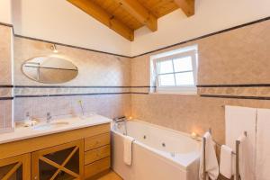 a bathroom with a tub and a sink and a mirror at Villas T3 com Jardim Vila Sagres in Sagres