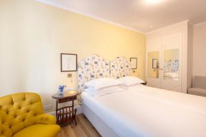 sypialnia z białym łóżkiem i żółtym krzesłem w obiekcie Kouneni Apartments w mieście Mykonos