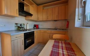 una pequeña cocina con armarios de madera y una mesa. en Ferienwohnung Mia en Brüggen