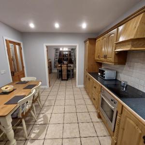 a kitchen with wooden cabinets and a table in it at Large private detached home in Dungiven