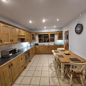 Large private detached home في Dungiven: مطبخ بدولاب خشبي وطاولة مع كراسي
