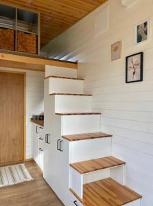 a tiny house with white walls and wooden shelves at Tiny house with garden and jacuzzi near Amsterdam in Vijfhuizen