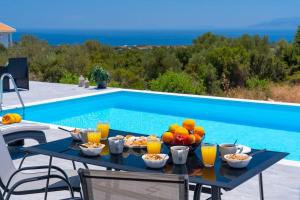 una mesa con fruta y bebidas junto a una piscina en Villa Laide en Kefallonia
