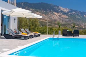 een zwembad met ligstoelen, een parasol en een zwembad bij Villa Laide in Kefallonia