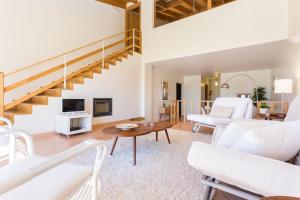 una sala de estar con muebles blancos y una escalera. en Villas T3 com Jardim Vila Sagres, en Sagres