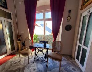 a table and chairs in a room with a window at Sissy Vendégház in Târgu Secuiesc