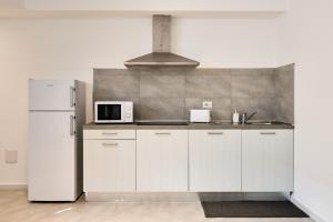 uma cozinha com armários brancos e um frigorífico branco em Corallo House Alghero em Alghero