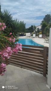 une clôture en bois à côté d'une piscine avec des fleurs roses dans l'établissement Mimosas - villa, à Fréjus