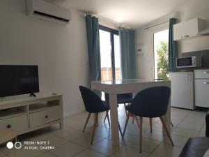 a living room with a table and chairs and a television at Mimosas - villa in Fréjus