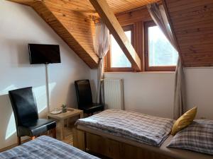 sypialnia z 2 łóżkami, telewizorem i krzesłem w obiekcie Penzión Pegas w Bratysławie