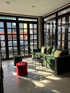 sala de estar con sofá verde, mesas y ventanas en BALÉ en Malabañas