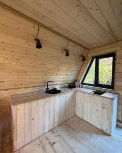 - une cuisine dans une cabane en bois avec une fenêtre dans l'établissement Схованка, à Yaremtche