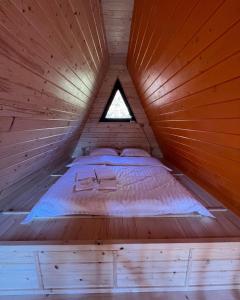a bed in a wooden cabin with a window at Схованка in Yaremche