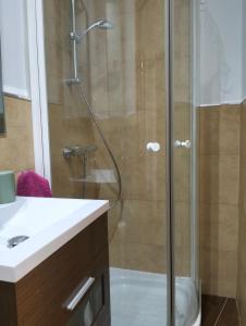 een douche met een glazen deur naast een wastafel bij La corrala de Malasaña in Madrid