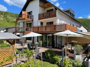 una casa con balcone, tavoli e ombrelloni di Haus Schatzgarten a Traben-Trarbach