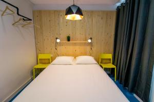 sypialnia z dużym białym łóżkiem z 2 żółtymi krzesłami w obiekcie Koala Hostel w Alicante