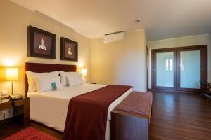 a bedroom with a large white bed and a wooden floor at Vila Gale Cascais in Cascais