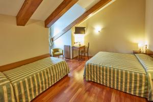 a hotel room with two beds and a desk at Liberty Hotel in Turin