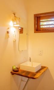 uma casa de banho com um lavatório branco num balcão de madeira em Pousada Tangerina em Icaraí