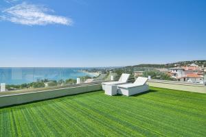 瓦爾納的住宿－Sea lounge，绿色草坪上的阳台配有两把白色椅子