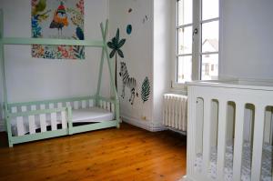 a nursery with white cribs in a room with wood floors at L'auberge du lavoir, maison en pierres avec jardin in Cairon