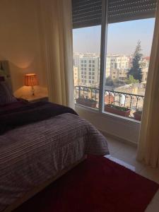 um quarto com uma cama e uma grande janela em Beautifull New 2 Bedroom Apartment in Amman em Amã