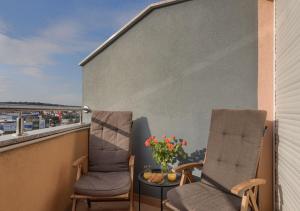 2 stoelen en een kom bloemen op het balkon bij Apartment Leki - newly renovated, modern city spot in Pula