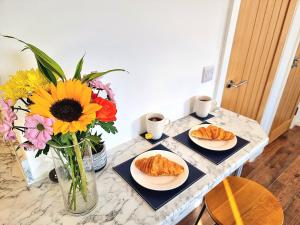 twee borden croissants op een tafel met bloemen bij Modern Apt near Train Station and Ideal for Long Stays in Leicester