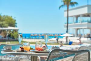 a table with a plate of food and wine glasses at So Nice Club Resort in Ayia Napa