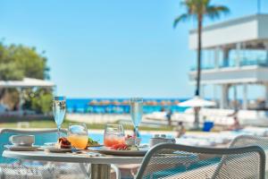 a table with a plate of food and wine glasses at So Nice Beach Resort in Ayia Napa