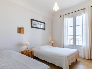 a white bedroom with two beds and a window at Apartment Foncillon by Interhome in Royan