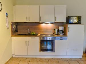 eine Küche mit weißen Schränken, einer Spüle und einem Kühlschrank in der Unterkunft Apartment Tjalkstrasse-3 by Interhome in Norddeich