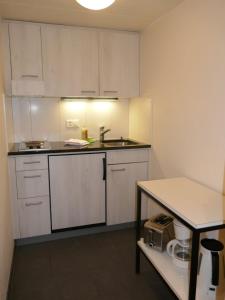 a small kitchen with white cabinets and a table at Apartment Schwendihus by Interhome in Grindelwald +24 photos