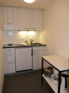 eine kleine Küche mit weißen Schränken und einem Tisch in der Unterkunft Apartment Schwendihus by Interhome in Grindelwald